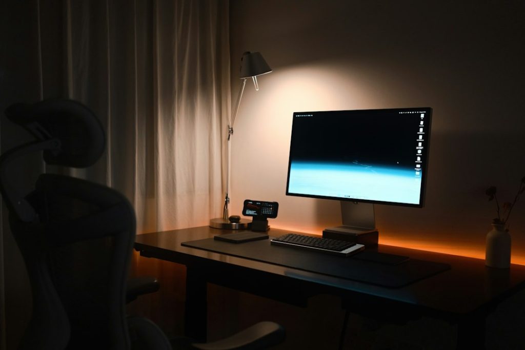 Desktop computer setup illuminated by warm workspace lighting