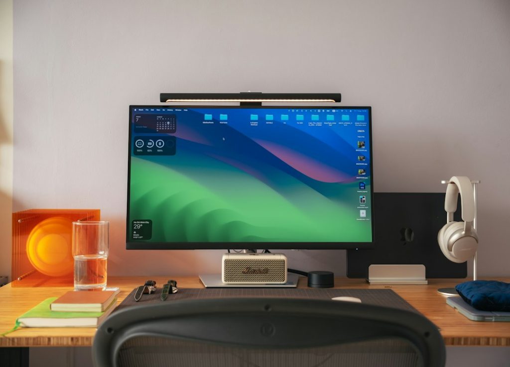 Computer monitor with a green desktop background on a wooden desk