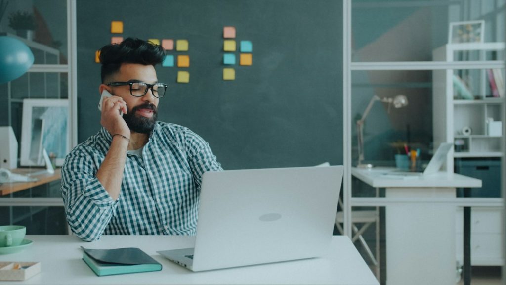 Person working at a computer while speaking on a phone