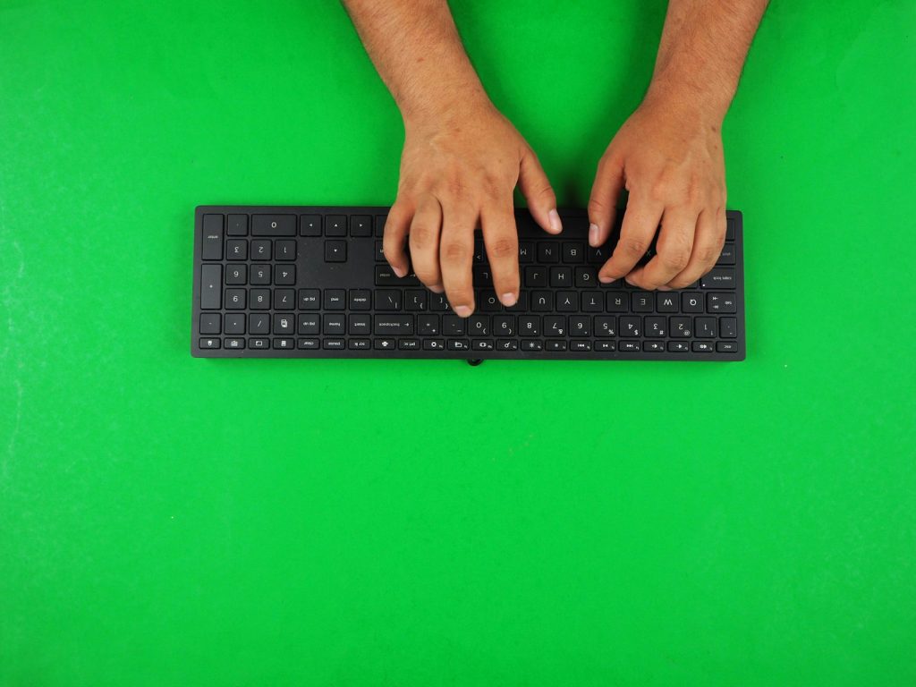 Hands typing on a keyboard while working at a desktop computer
